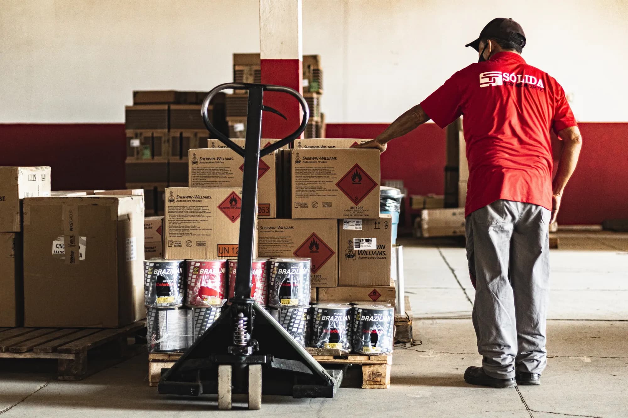Colaborador da Sólida organizando volumes em pallet com paleteira manual