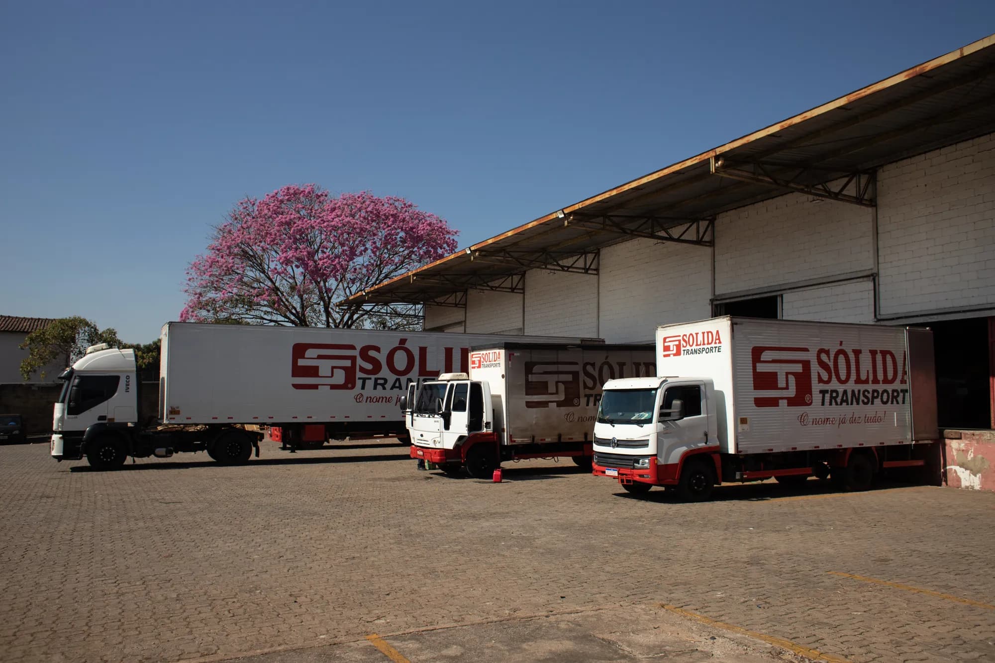 Carreta e caminhões baú da Sólida enfileirados em frente ao galpão